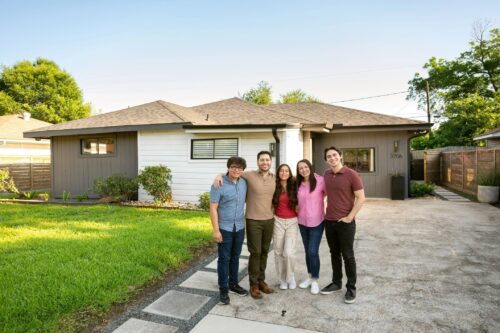Family with three teens portrait in front their suburban home
