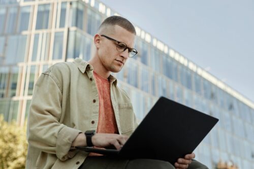 Businessman in Glasses Using Laptop to Work Outdoors in City