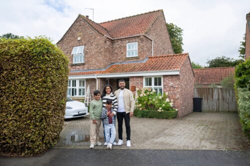 Wide shot of British Pakistani family outside house