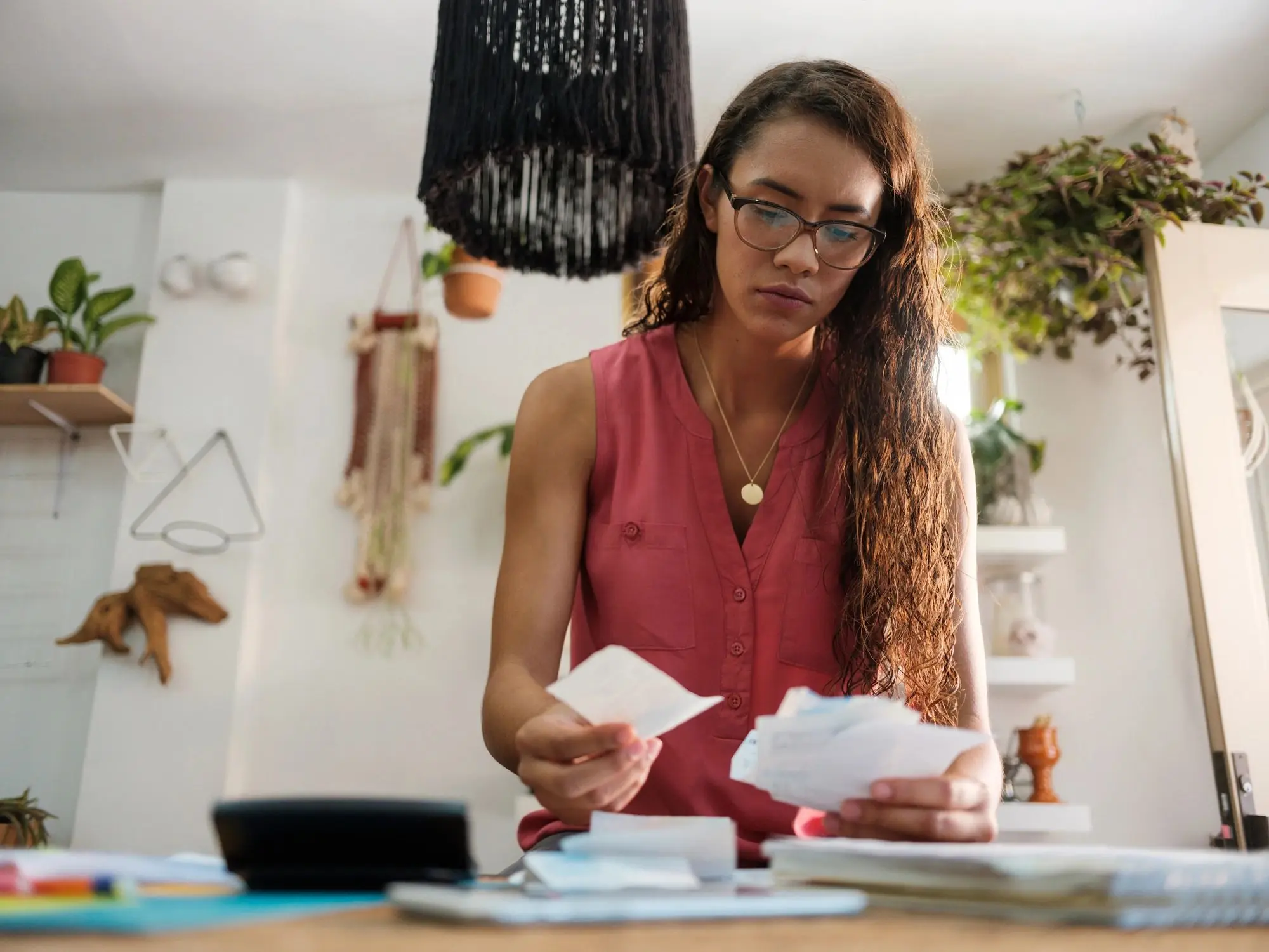 Young latin woman holding receipts and looking at them.