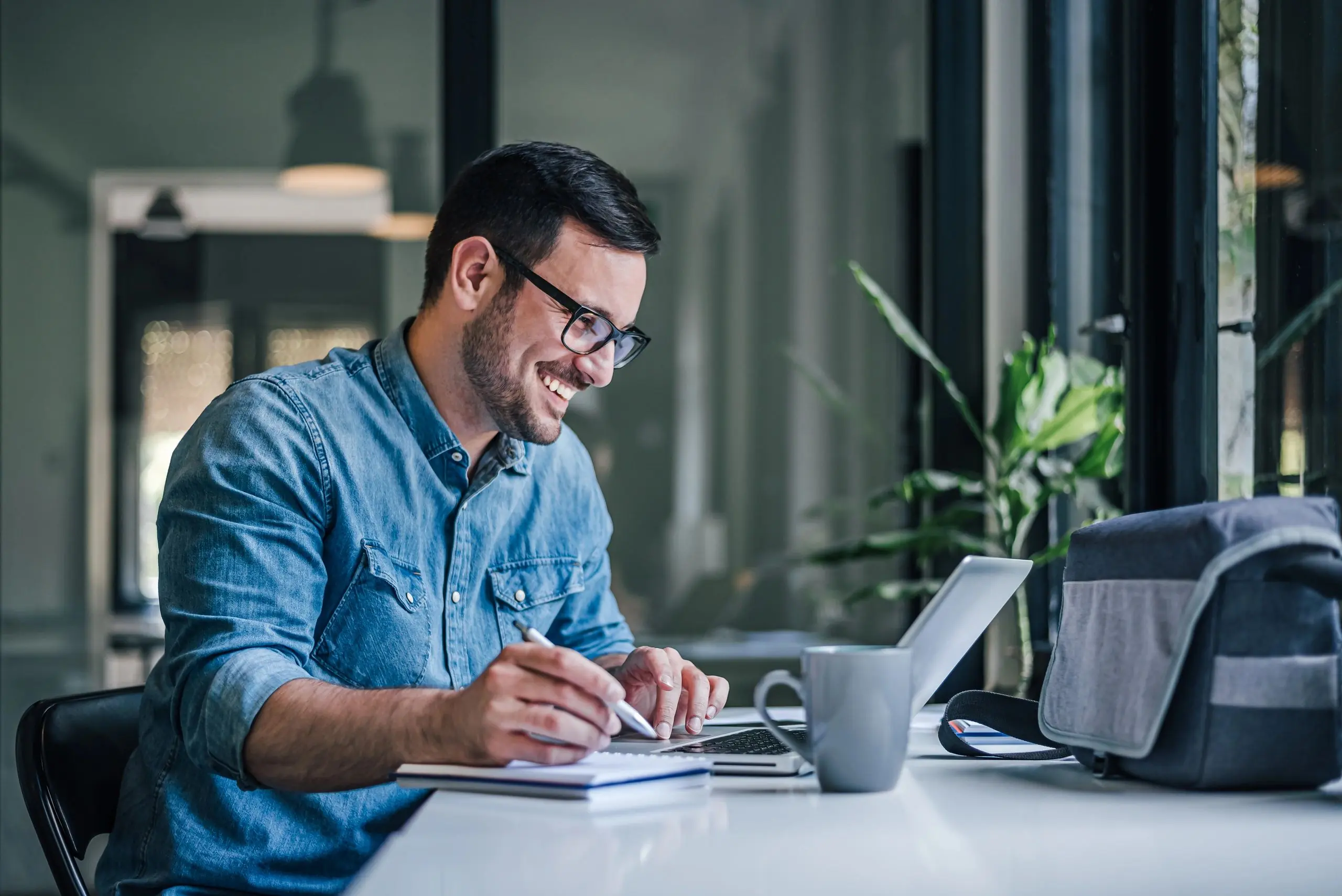 Smiling adult man, writing down his earnings for the month.