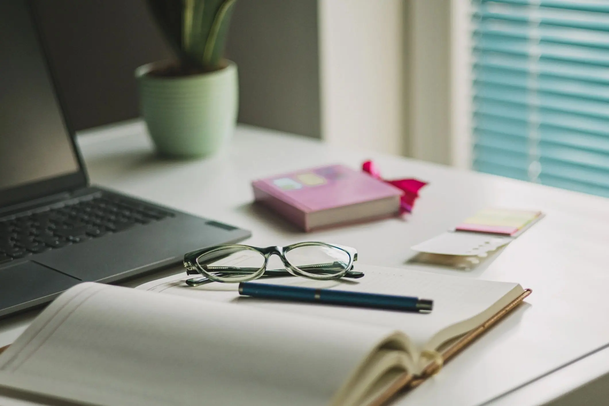 Desk with laptop, coffee, and reading glasses for writing and editing content