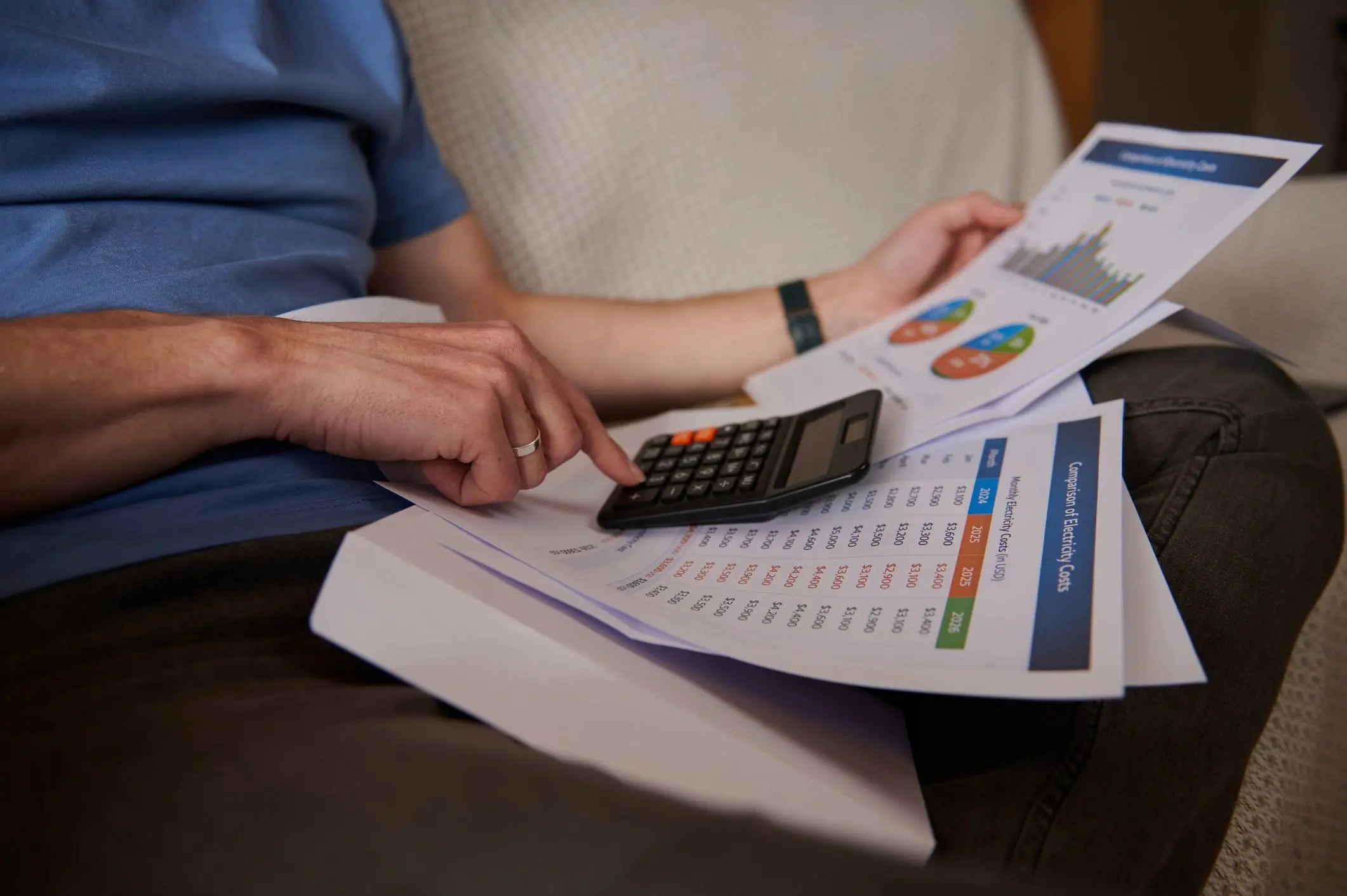 Man Calculating Household Bills With Calculator and Financial Documents on Couch