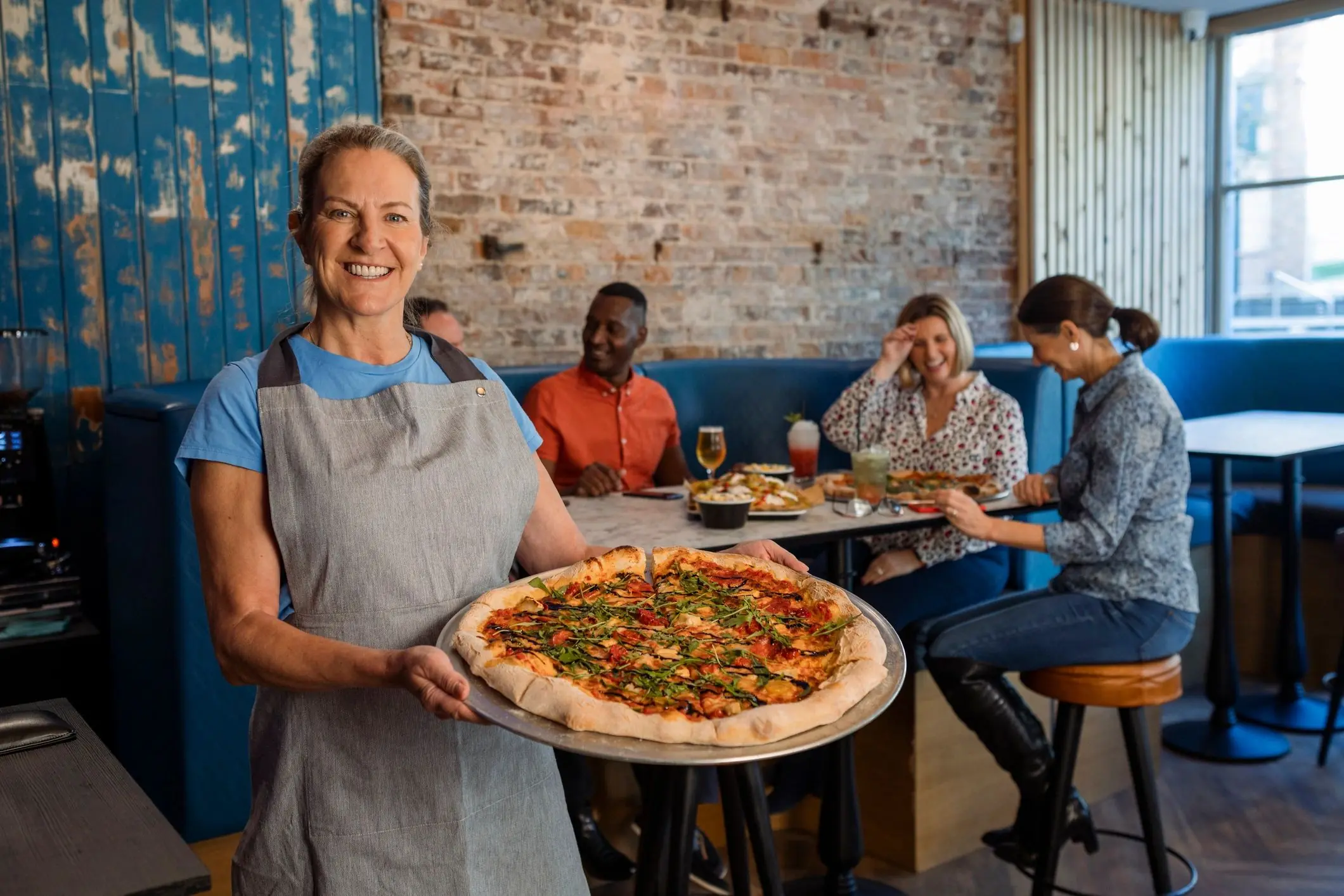 Server bringing pizza to a restaurant table